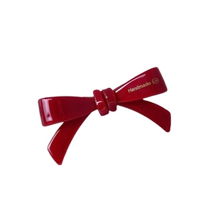Elegant red acetate bow hair clip with gold handmade lettering on white background