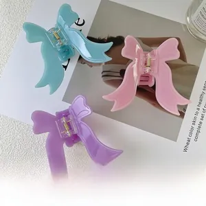 Trois élégantes pinces à cheveux papillon en acétate bleu rose et violet sur fond de magazine