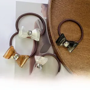 Detailed view of acetate bow hair ties with rhinestones on a wooden tray