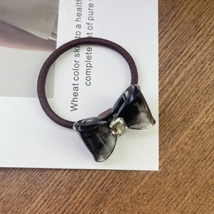 Detail view of acetate bow hair tie with rhinestone inlay on elastic band