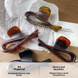 Detailed view of large shark hair clips in amber, tortoiseshell, and matte black finishes