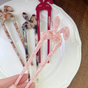 Close-up of rabbit-shaped acetate U-shaped hairpins in pink and tortoiseshell finishes