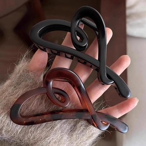 Detail view of large irregular heart hair claws in glossy black and tortoise shell finish