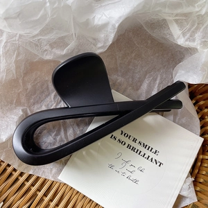Macro view of matte black hair claw clip on aesthetic background with basket