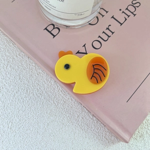 Close-up of a cute yellow chick hair clip made of resin on a pink book background