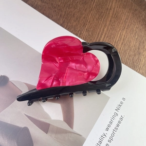 Detail van bordeauxrode marmeren hart haarklem met zwart frame op houten oppervlak