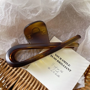Detail of elegant amber tortoiseshell hair claw clip resting on a white card