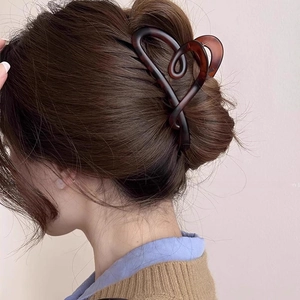 Detail of a large amber heart hair claw clip styled on a low bun for elegant women