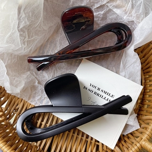 Detail of large shark hair claws in dark amber and matte black on a woven basket background