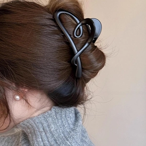 Detail view of large matte black heart hair claw clip on model with pearls