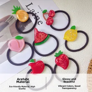 Close-up of seven acetate fruit-themed hair ties including strawberry and apple designs