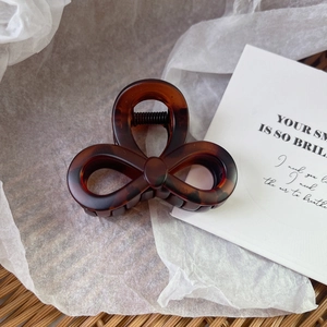 Close-up of a brown tortoiseshell hair claw clip with a clover-shaped bow design