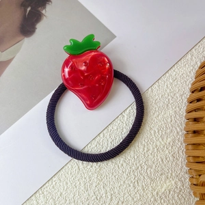 Detailed macro shot of a strawberry hair tie with sparkling rhinestones and green leaves