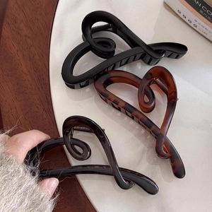 Elegant irregular heart-shaped hair claws in black and tortoiseshell finish on white background