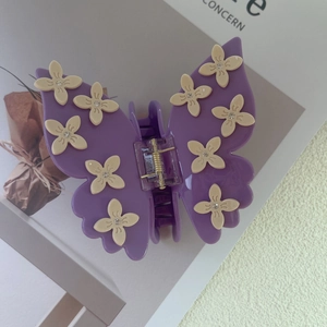 Detail shot of a purple butterfly hair claw with cream floral accents and sparkling rhinestones