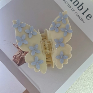 Close-up of butterfly hair claw clip with light blue floral accents and crystal rhinestones