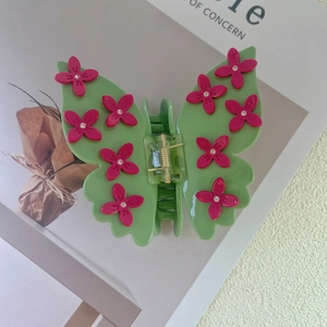 Close-up of green butterfly hair claw clip with pink flowers and sparkling rhinestones