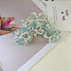 Detail view of acetate flower claw clip with marble texture and pearl center accent