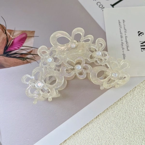 Macro detail of the floral acetate hair claw with delicate pearl accents and hollow design