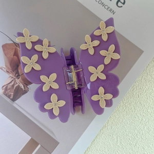 Close-up of purple butterfly hair claw clip with white rhinestones and flower details