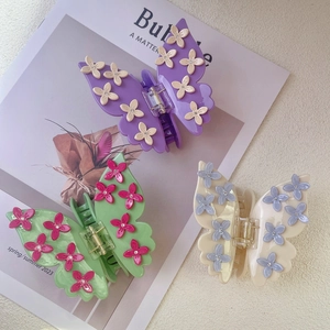 Three butterfly hair claws in purple, green, and beige with 3D flowers and crystals
