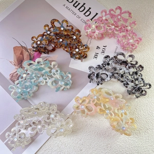 Detail of five hollow flower claw clips with pearls on an elegant magazine backdrop