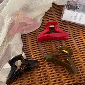 Set of four matte hair claw clips in pink, red, brown and green on a retro woven background