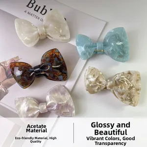 Set of five acetate bow hair clips in pearl white and marble patterns on a magazine background