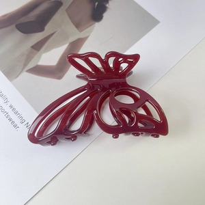 Close-up of hollow butterfly acetate hair claw clip in dark red with glossy finish