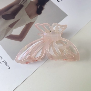 Detailed macro view of hollow butterfly hair claw with pink marble acetate texture