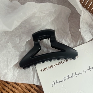 Detail shot of a matte black triangle shark hair claw clip with sleek geometric cutout design
