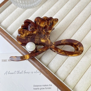 Détail de la pince à cheveux feuille de ginkgo ambre avec perle sur plateau bijoux