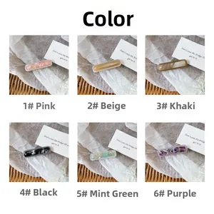 Detail view of acetate hair clips in six colors with marble texture on fabric background