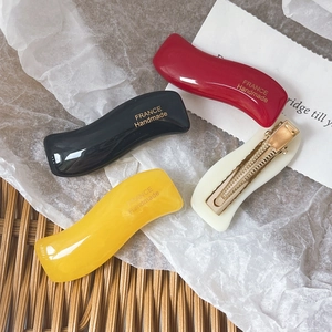 Set of four wavy candy-colored resin hair clips in red black yellow and white