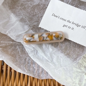 Detailed macro view of an acetate hair clip with amber floral pattern on white paper