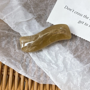 Detailed macro view of an amber marble resin hair clip with France Handmade lettering