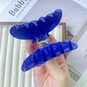 Gros plan d'une pince à cheveux bleu Klein brillante avec mécanisme à ressort métallique