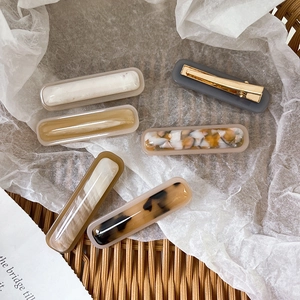 Set of 6 acetate hair clips with marble and tortoiseshell patterns in a wicker basket