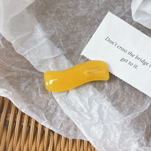 Detail of yellow wavy acetate hair clip with FRANCE Handmade text on white textured paper