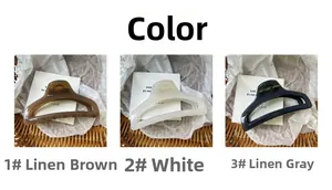 Tre pinze per capelli opache nei colori marrone, bianco e grigio su fondo neutro