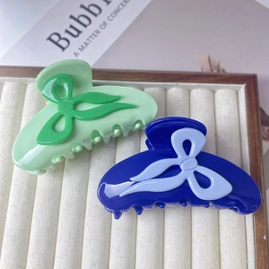Barrettes à cheveux nœud chic en vert clair et bleu marine sur un plateau beige
