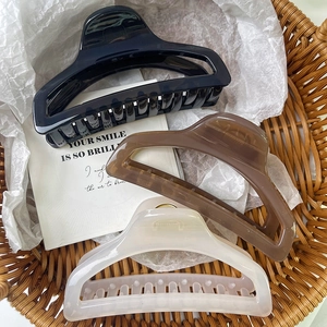 Tre grandi mollette per capelli in nero, ambra e bianco crema presentate in un cesto