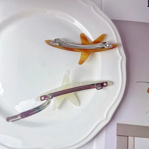 Vue détaillée de barrettes étoile de mer en acétate ambre et blanc nacré sur une assiette