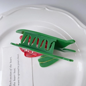 Détail d'une pince à cheveux tulipe avec strass sur une assiette en céramique