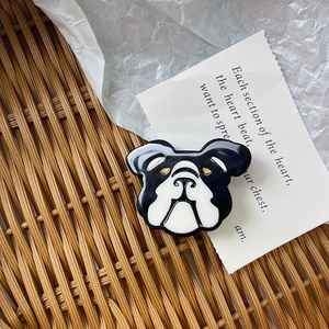 Detailed view of a bulldog enamel hair clip placed inside a decorative woven basket