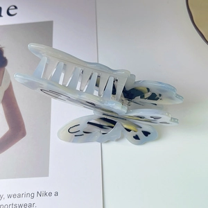 Detailed macro view of butterfly hair claw clip with pearlescent marble texture acetate