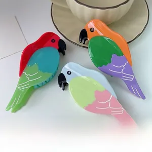 Dettaglio di tre mollette per capelli a forma di pappagallo in acetato colorato