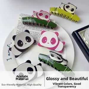 Dettaglio di pinze per capelli a forma di panda in acetato nero, rosa e verde su ceramica