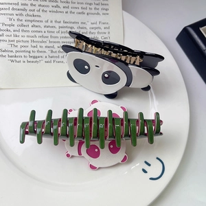 Dettaglio di simpatiche mollette per capelli panda in acetato nero e rosa su un piatto