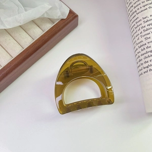 Detail of translucent olive green hair claw clip with golden spring on aesthetic background